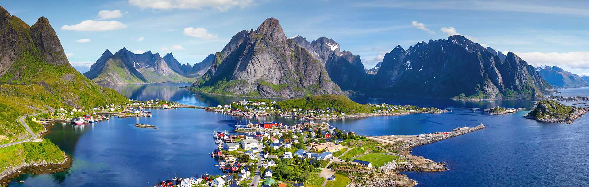 The village of Reine, Norway, under a sunny blue sky with the typical rorbu houses.