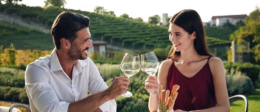 Happy couple enjoying romantic dinner with wine at a vineyard in Italy