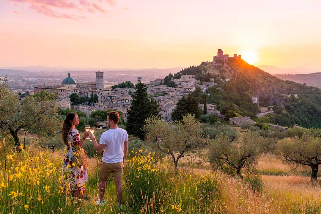 Couple Toasting Wineglasses at sunset in Assisi, Italy