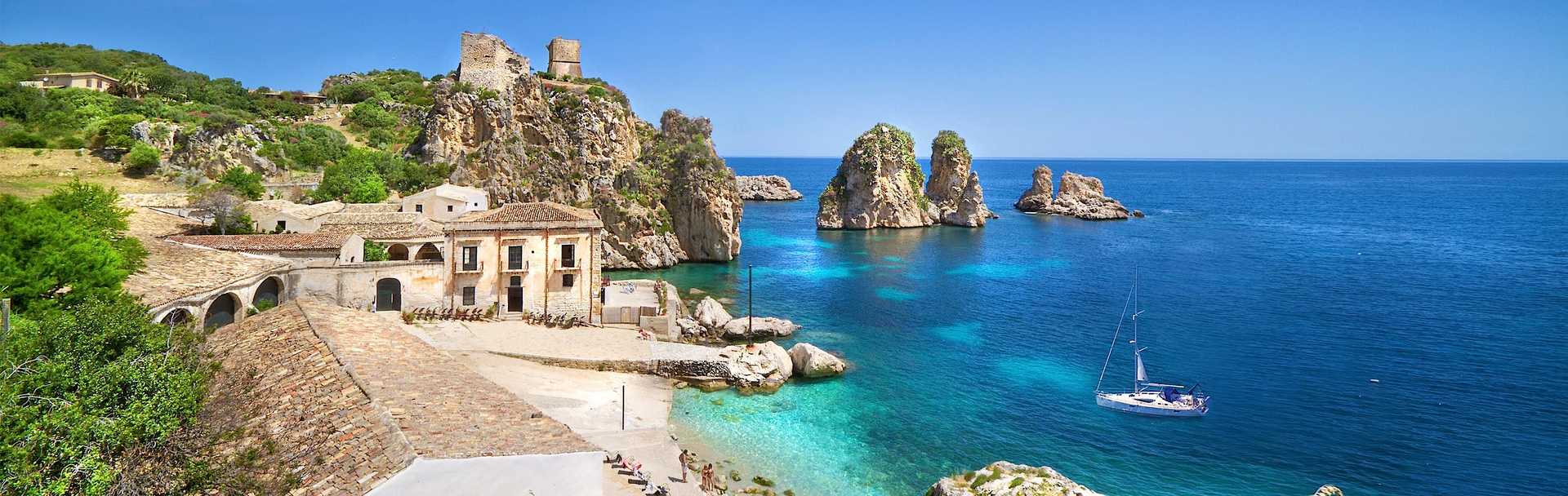 Small beach with clear blue water and rock formations at Tonnara di Scopello in Trapani, Sicily, Italy