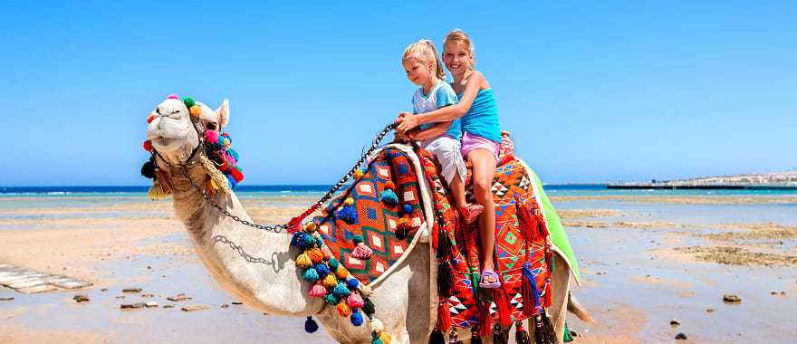 Sisters riding camel on the beach in Egypt