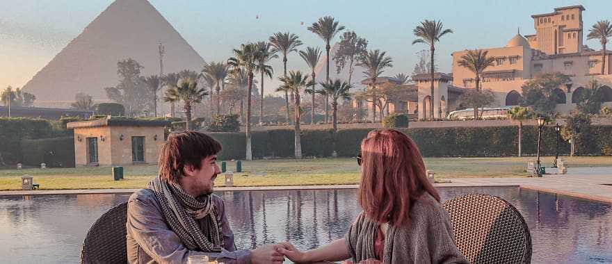 Couple enjoying breakfast with a view over the Pyramids of Giza in Egypt