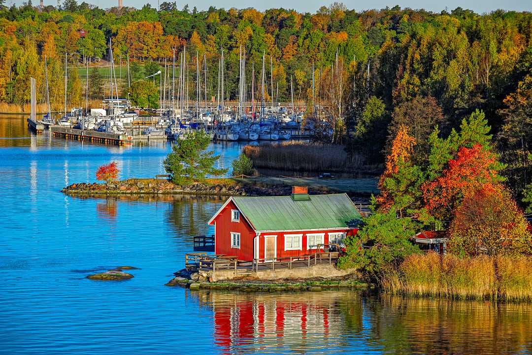 Red cabin and autumn forest on rocky shore of Ruissalo island, Turku Archipelago, Finland