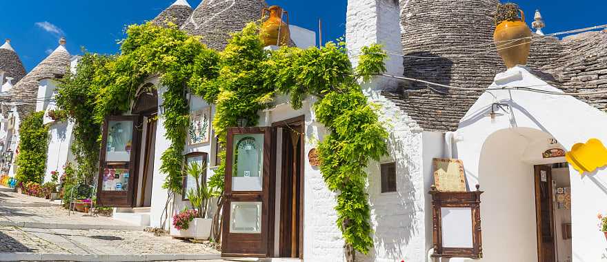 Beautiful town of Alberobello with trulli houses among green plants and flowers in the Apulia region of southern Italy.