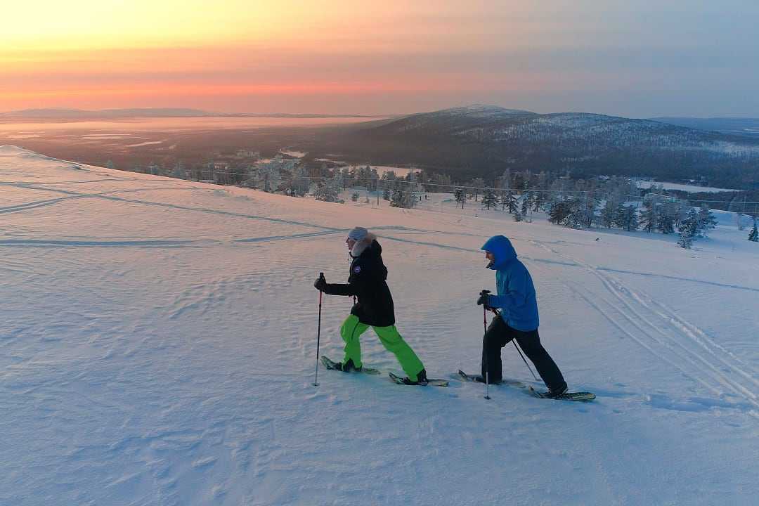 Couple snowshoeing at sunset in Lapland, Finland