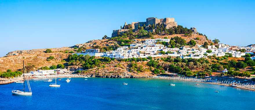 Lindos acropolis on hill above white houses and blue ocean bay in Rhodes, Greece