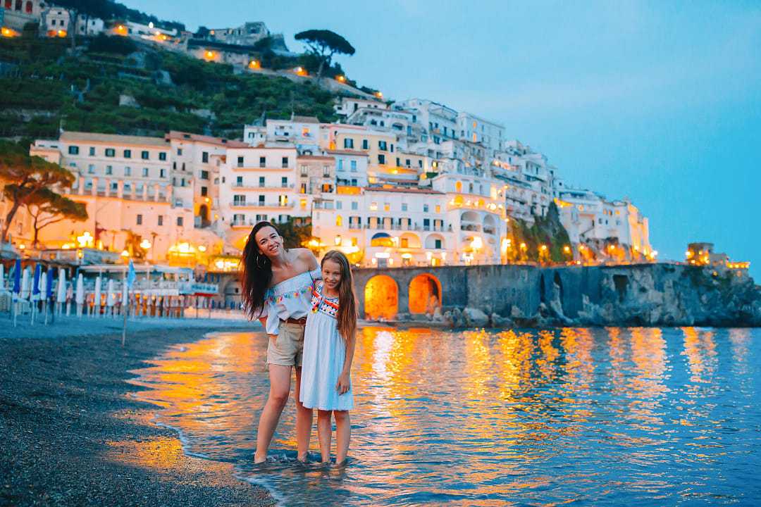 Mother and daughter on the beach at dusk in Amalfi, Italy