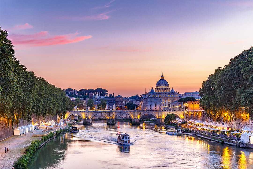 Dusk on a summer evening along the Tiber river with night market in Rome, Italy