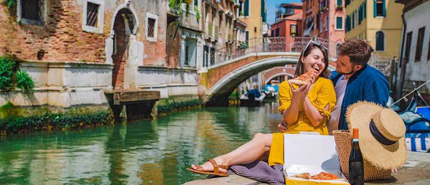 Couple enjoying a romantic picnic along a canal in Venice, Italy