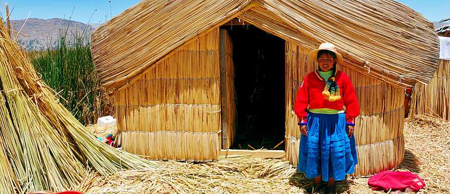 A girl standing on a floating Uros island standing in front of her home in Lake Titicaca, Peru.