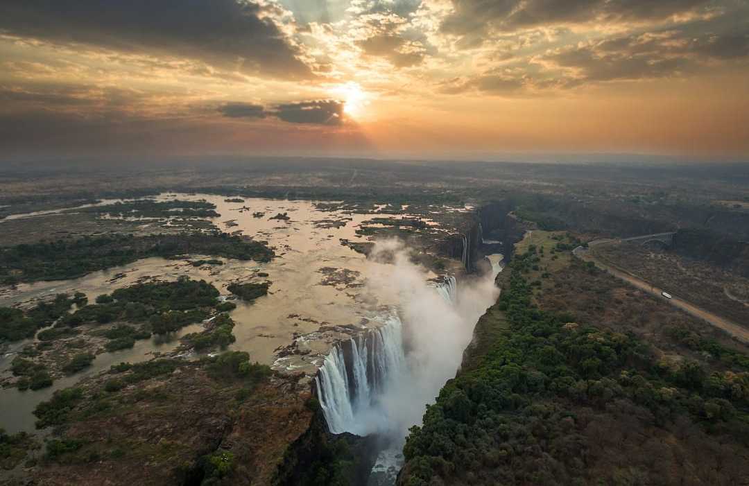 Victoria Falls on the Zambezi River in Zimbabwe, Africa The mighty Victoria Falls cascades dramatically at sunset over Zambezi River.
