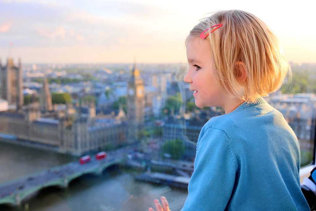 Little girl at sunset observing the Westminster Abbey in London 