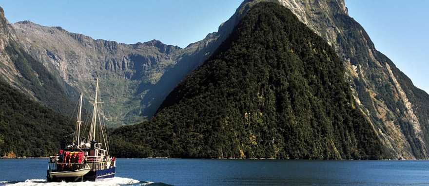 Ship under Mitra Peak in Fiordland National Park on South Island, New Zealand Ship under Mitra Peak in Fiordland National Park on South Island, New Zealand