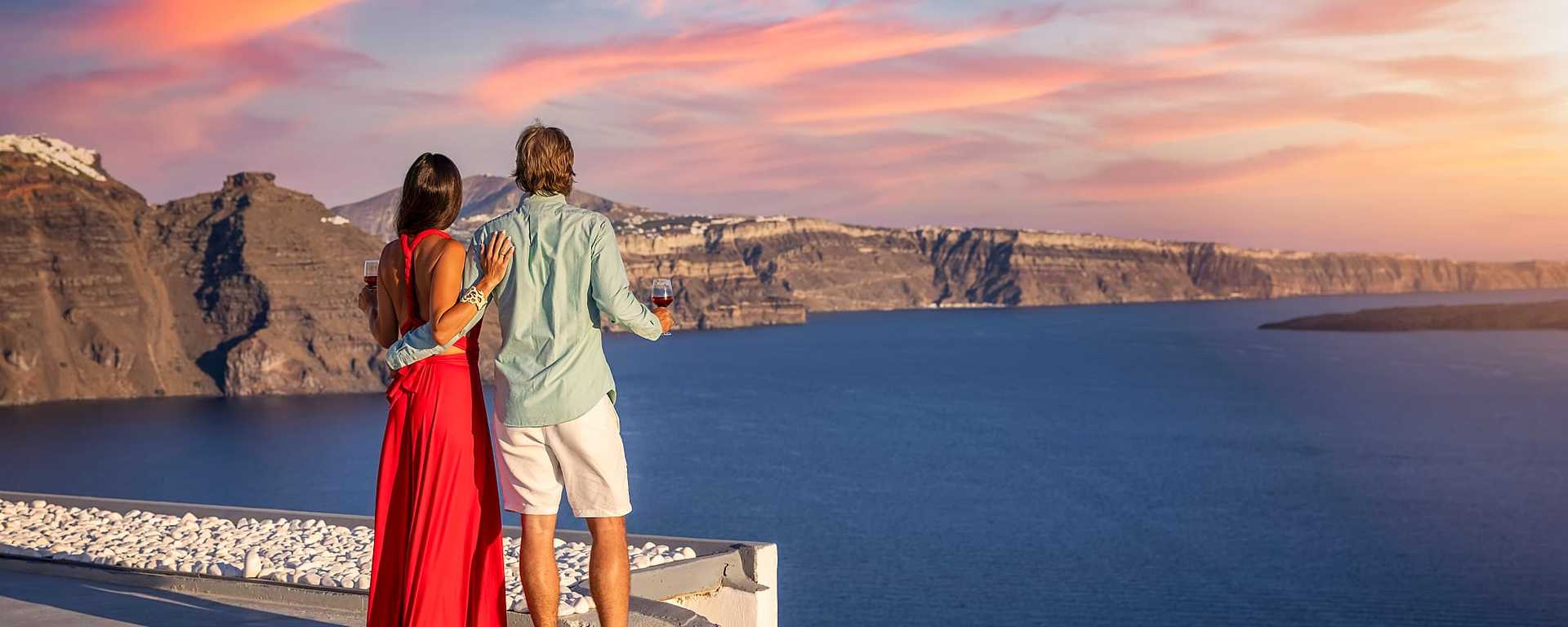 Couple drinking wine and watching the sunset in Santorini, Greece