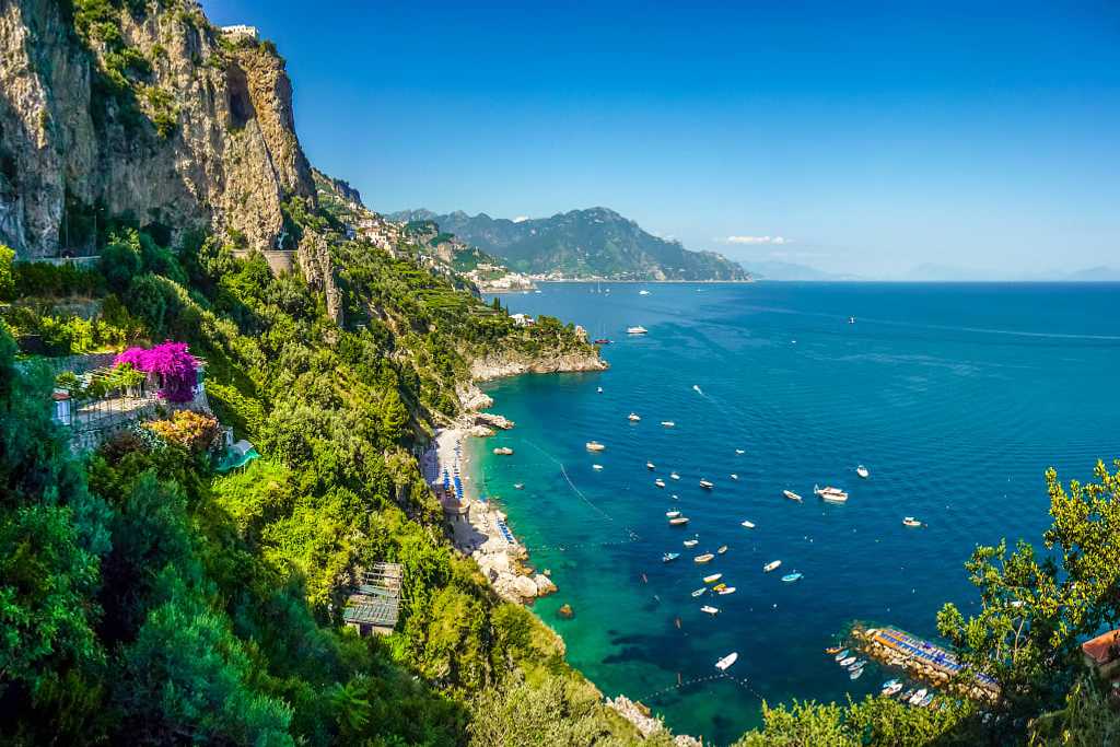 Postcard view of steep mountain cliffs and azure waters in the Amalfi Coast of Italy