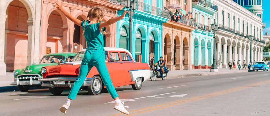 Girl in the street with vintage classic American car in old Havana, Cuba