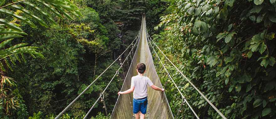 Child crossing hanging suspension bridge in the jungle of Costa Rica