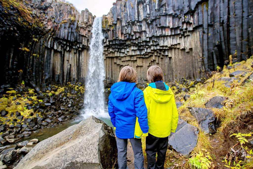 Young siblings at Svartifoss waterfall in Iceland