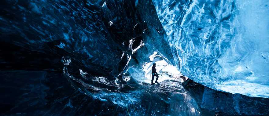 Mountain climber standing inside ice cave glacier