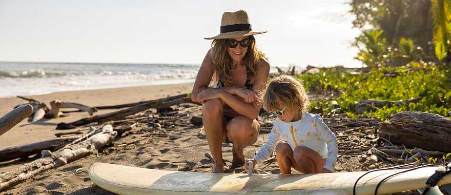A young girl learning how to wax a surf board from her mother in Costa Rica