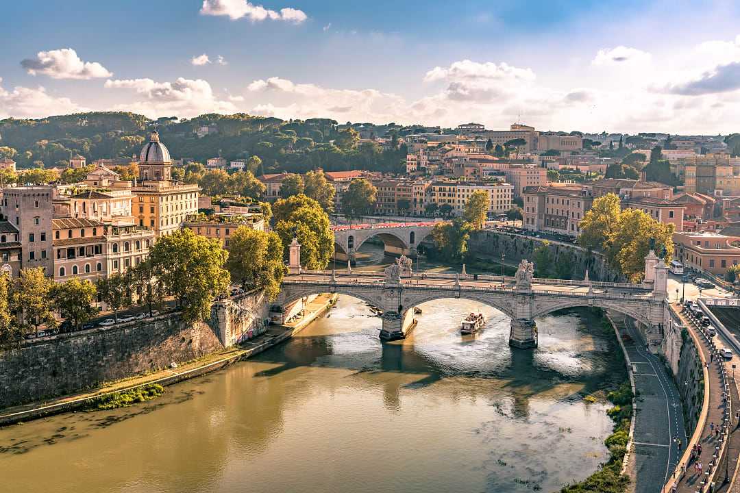 Elegant bridge spans Tiber River with Rome’s skyline behind.