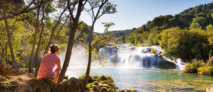 Woman traveler relaxing and viewing the waterfalls in Krka National Park, Croatia