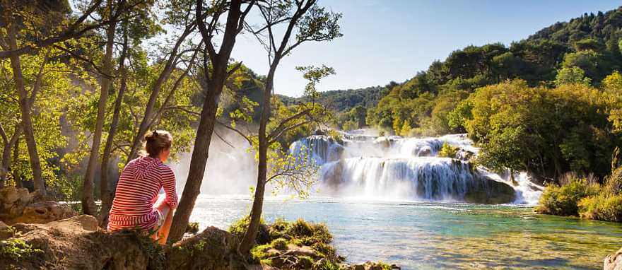 Croatia Tour for Seniors: Sophistication and Adventure Woman traveler relaxing and viewing the waterfalls in Krka National Park, Croatia
