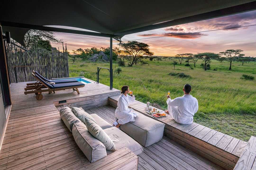 Coule watching the sunrise from the deck of their luxury tent Lemala Nanyukie in Serengeti National Park, Tanzania