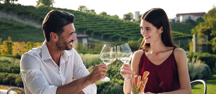 Happy couple enjoying romantic dinner with wine at a vineyard in Italy