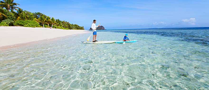 Father and son stand up paddle boarding in Fiji