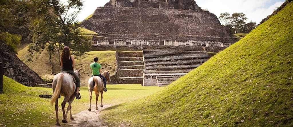 Xunantunich in Cayo District, Belize. Photo courtesy of Kaana Resort Couple horseback riding to the ancient Maya ruins of Xunantunich in Cayo District, Belize