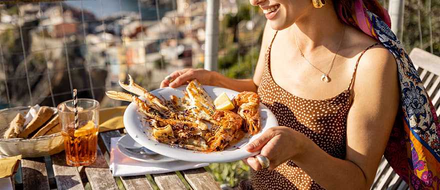 Woman enjoying Liguirian cuisine outdoors with a view in Vernazza, Cinque Terre, Italy