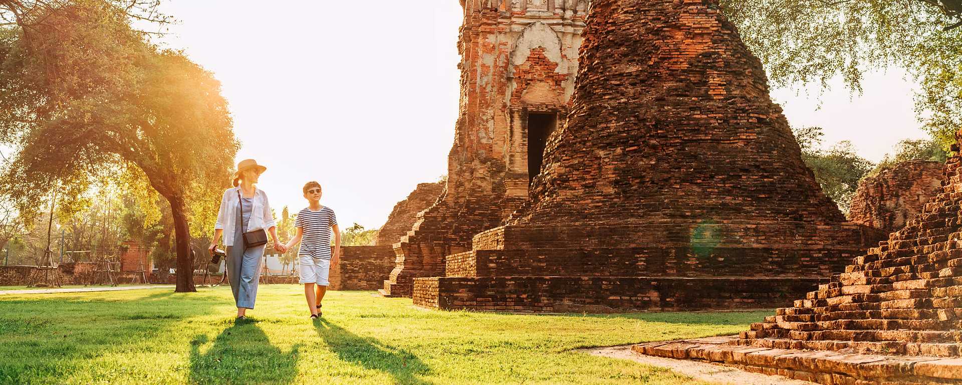 Mother and son tourists walking hand in hand in Wat Chaiwatthanaram ruines in Ayutthaya, Thailand 