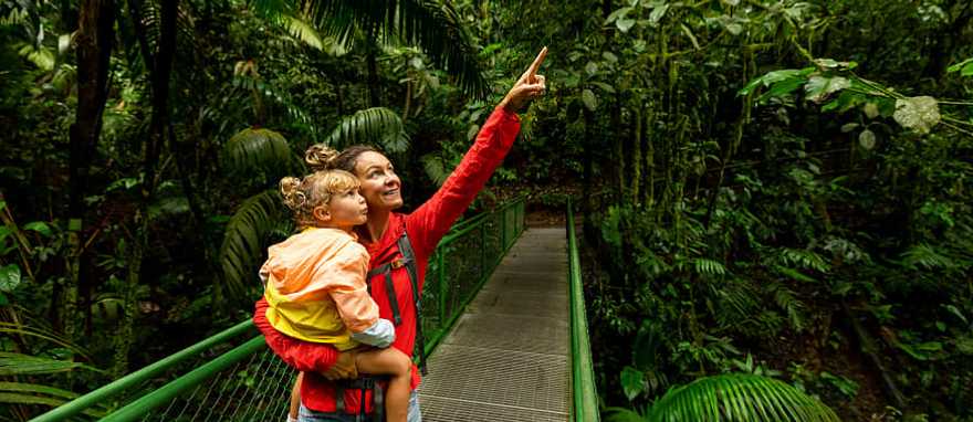 Classic Family Costa Rica Vacation "Mother and child on a rainforest walkway in Arenal, Costa Rica, exploring and pointing at the lush greenery.