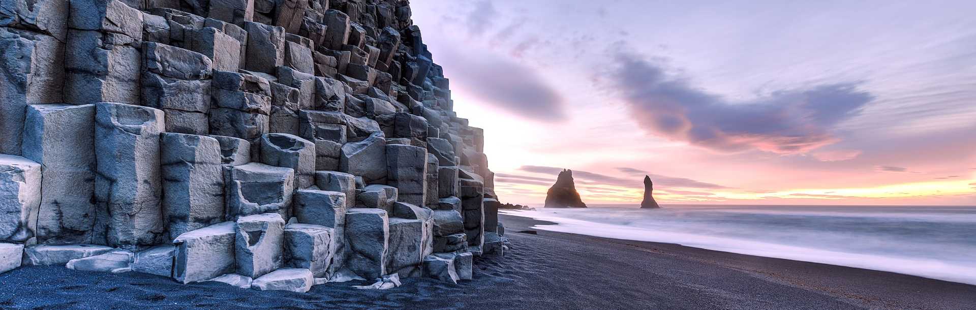 Reynisdrangar rock formations on Reynisfjara beach at sunrise, in Halsanefhellir, Iceland.