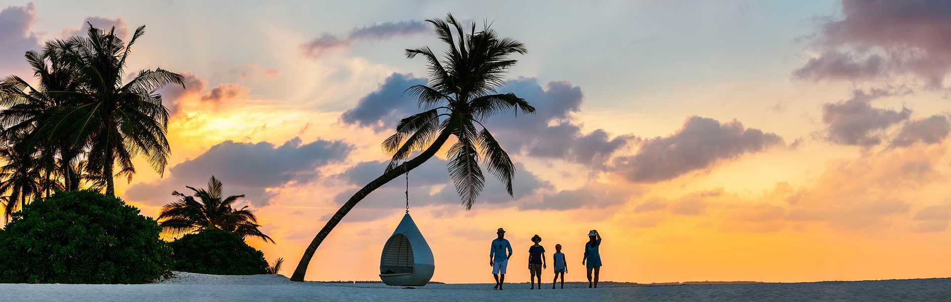 Family walking on the beach in the Maldives at sunset