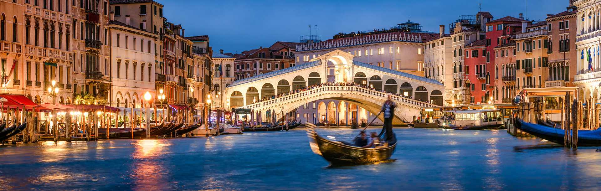 Couple enjoying a romantic gondola ride near Rialto Bridge in Venice at night