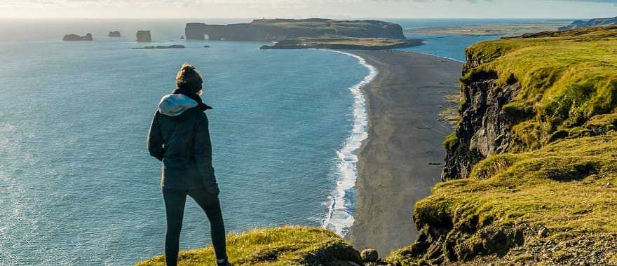 Hiker enjoying view of Reynisfjara black sand beach and Dyrholaey in the distance