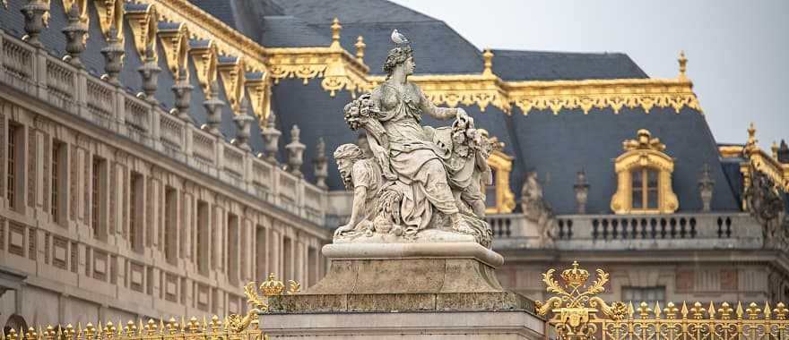 Statue and ornate architecture of Versailles in France.