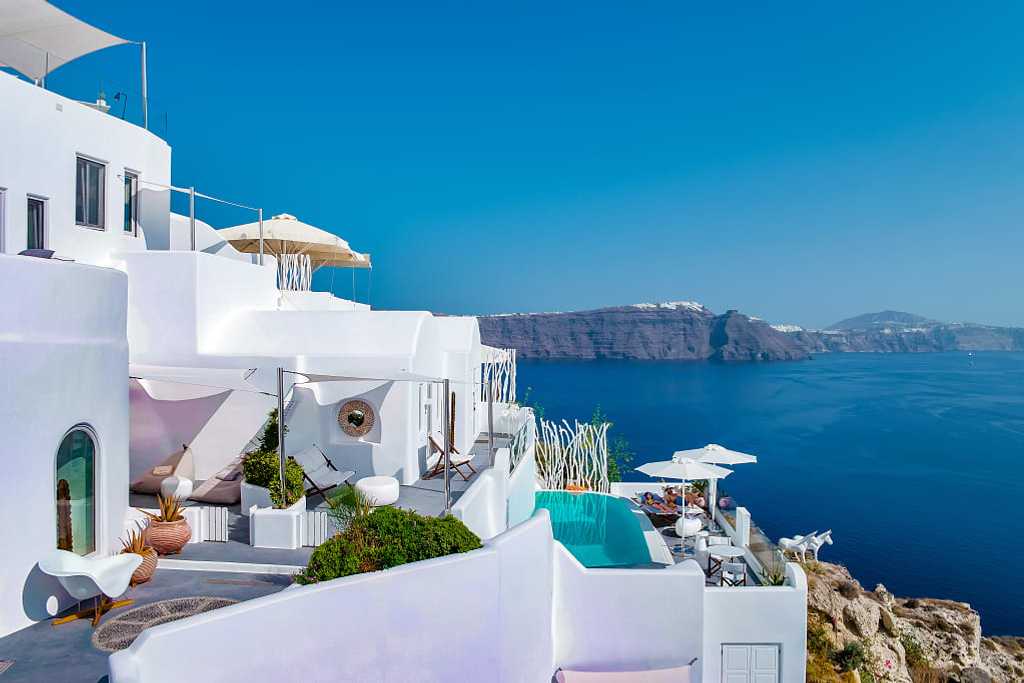 Couple lounging poolside at boutique luxury hotel in Santorini, Greece