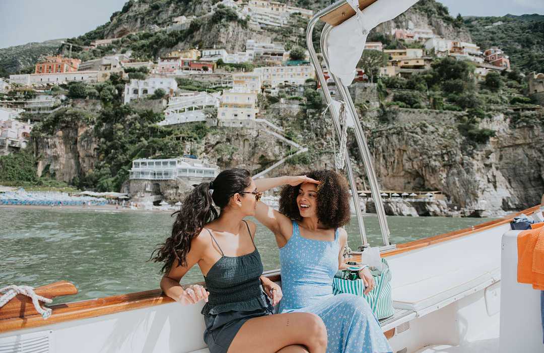 Amalfi Coast, Italy Two women enjoying a boat ride along the Amalfi Coast, Italy, with colorful cliffside villages in the background
