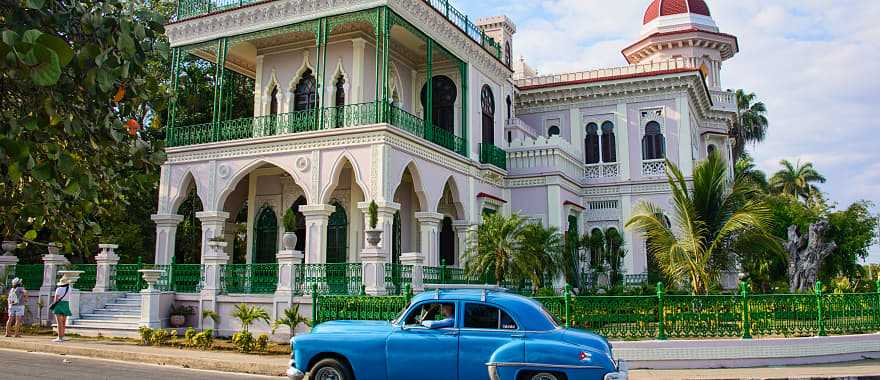 Vintage car passing by Palacio de Valle in Cienfuegos, Cuba