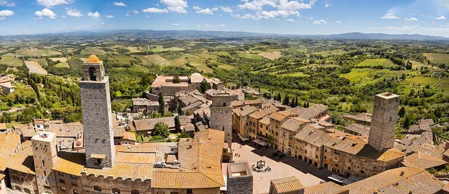 San Gimignano surrounded by the green rolling hills and vineyards of Tuscany, Italy