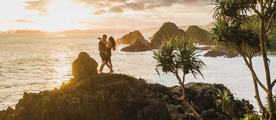 Honeymoon couple at sunset on the rock in Bali, Indonesia Honeymoon couple at sunset on the rock in Bali, Indonesia