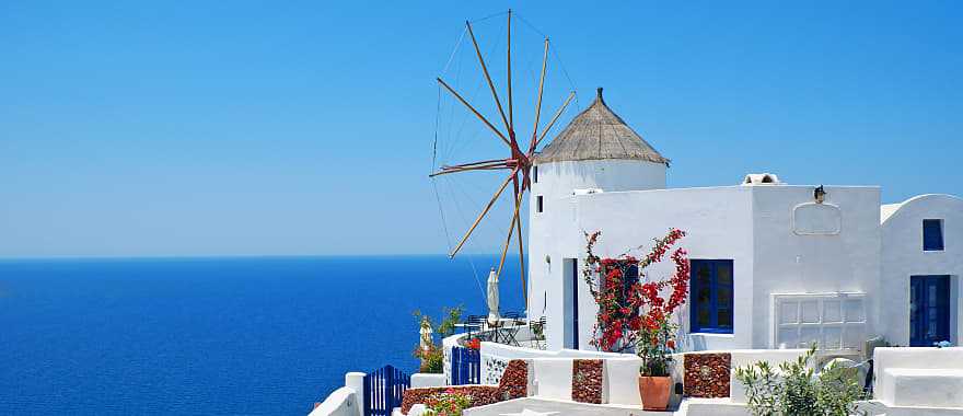 Windmill and white house with clear blue sky and ocean in Santorini