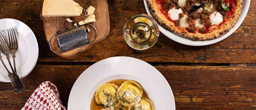 Ravioli, pizza and wine on rustic restaurant table in Italy