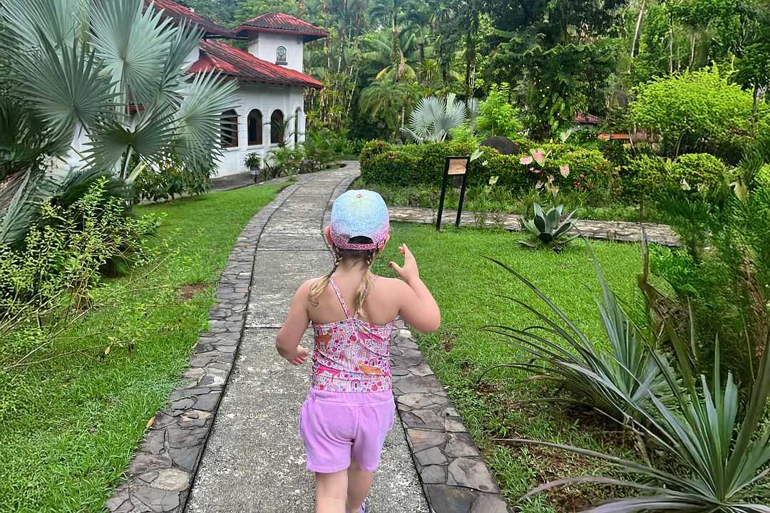 Young girl walking along a stone path surrounded by lush tropical greenery at a luxury resort in Costa Rica