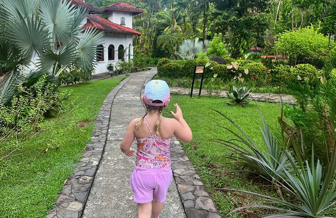 Young girl walking along a stone path surrounded by lush tropical greenery at a luxury resort in Costa Rica