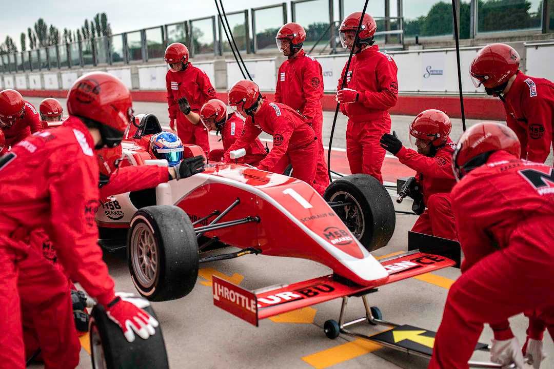 Pit crew changing tires on formula 1 race car during pit stop in Italy.