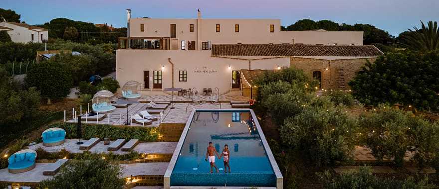 Couple at a luxury resort pool surrounded by vineyards in Selinunte, Sicily